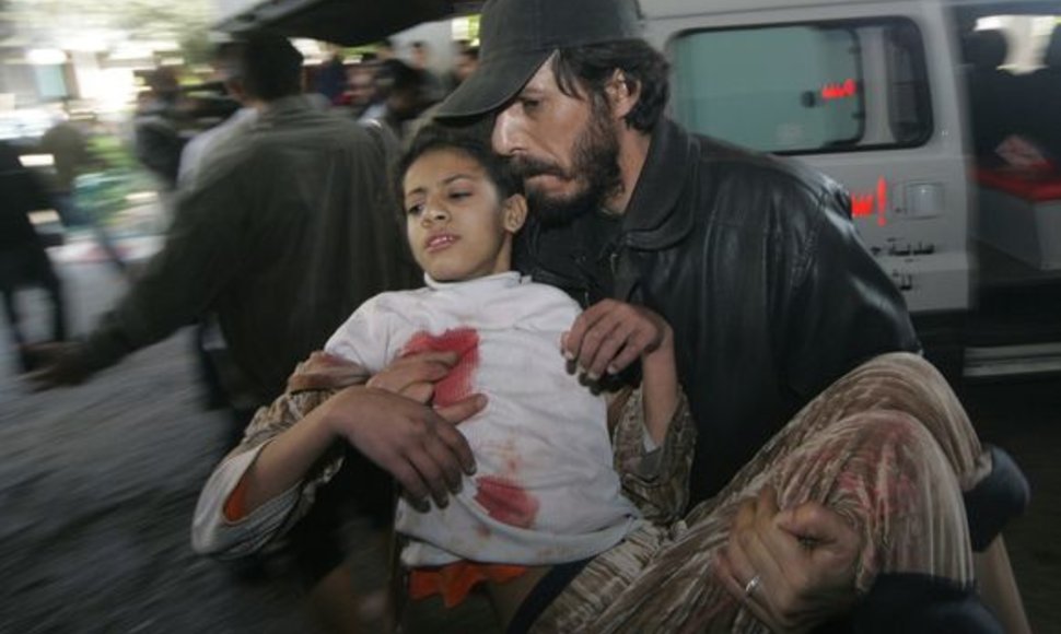 Vyras neša sužeistą mergaitę Gazos ruože.