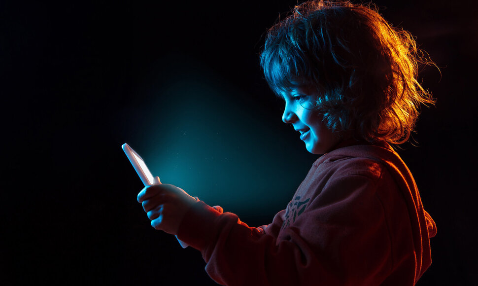 Caucasian boy's portrait isolated on dark studio background in neon light