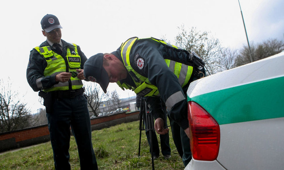 Kelių policininkas ant automobilio klijuoja lipduką „Aš neimu kyšio“