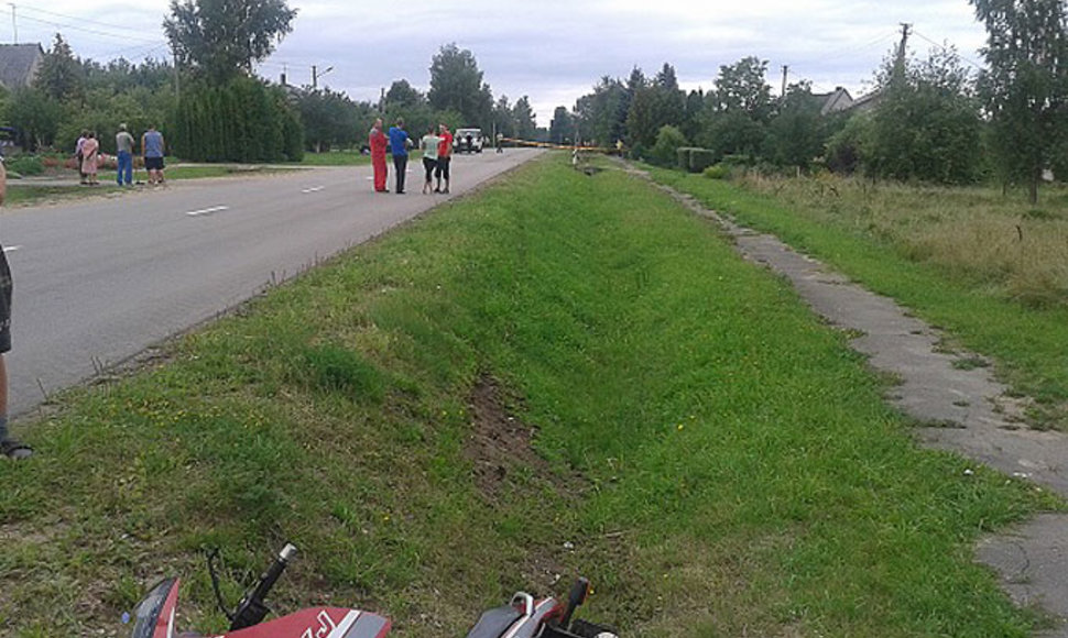 Avarijos vietoje Trakiškių kaime. Tolumoje galima įžiūrėti policijos mikroautobusą, greta stovi automobilis, į kurį atsitrenkė motociklas. Po smūgio motociklas dar skriejo keliasdešimt metrų