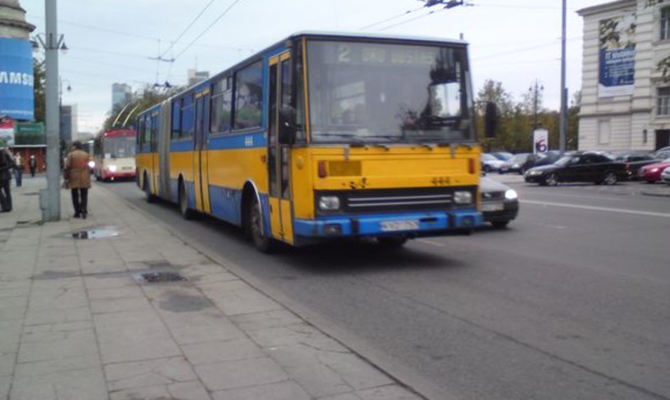 Miesto maršrutinis autobusas veža keleivius be artimųjų šviesų.