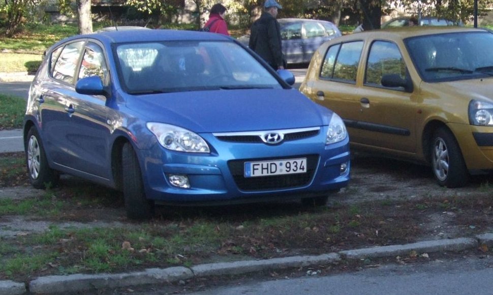Mėlynasis prokurorės automobilis ant išvažinėto žolės ploto sostinės Žirmūnų rajone.