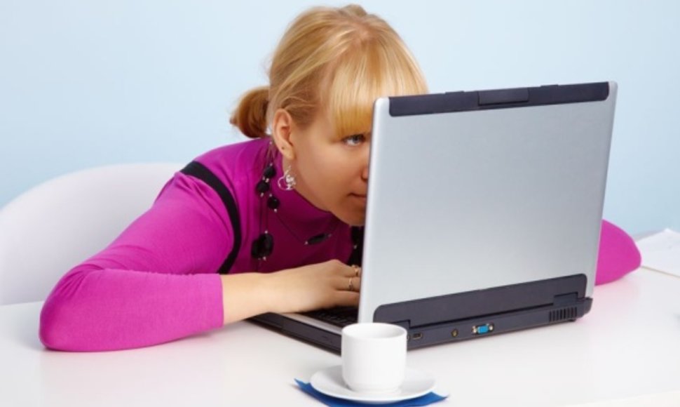 Moteris akylai žiūri į kompiuterio ekraną