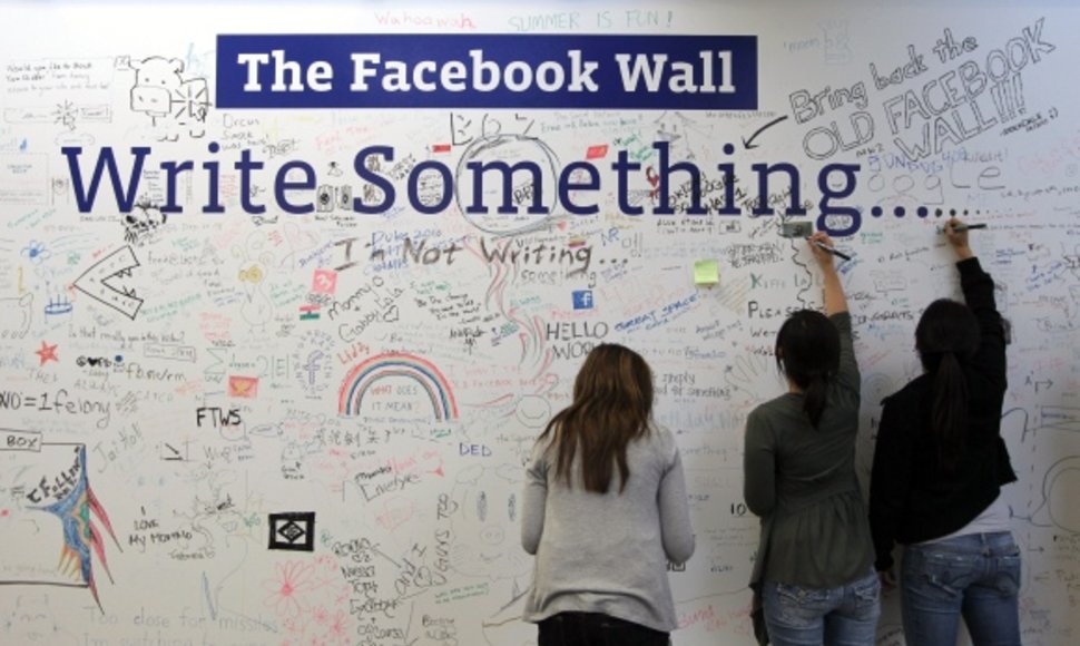 „Facebook“ darbuotojai rašo ant specialiai tam skirtos sienos, įrengtos kompanijos būstinėje.