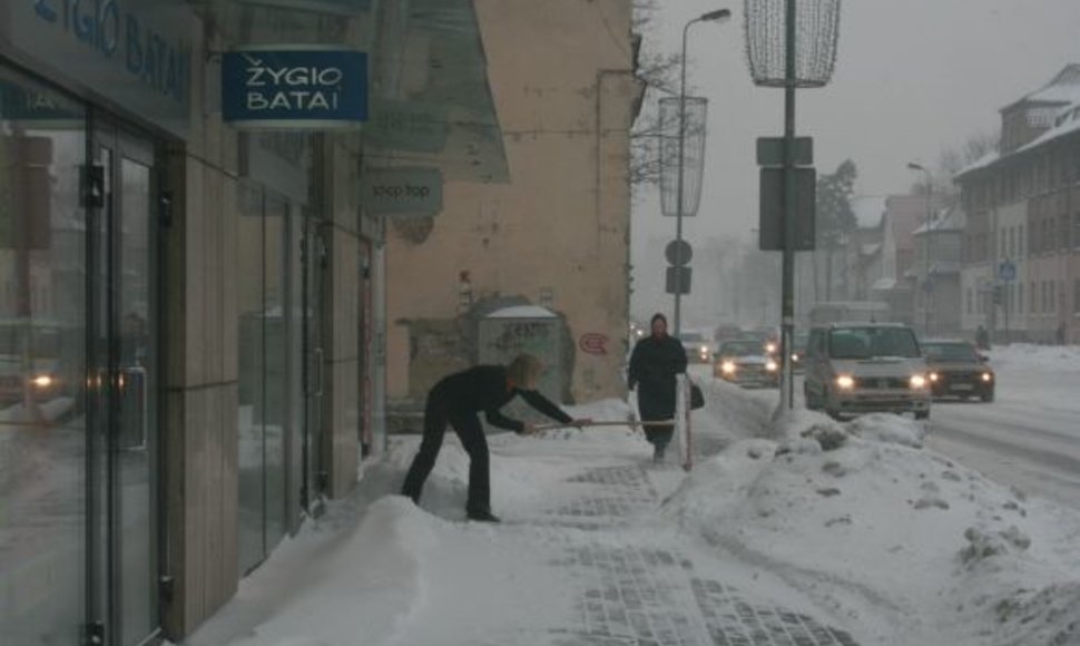 Parduotuvių darbuotojai ryte kasė praėjimus užgriuvusį sniegą. 