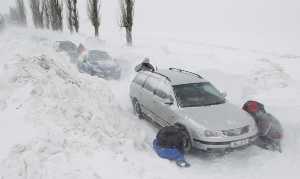 Vyrai deda ant automobilių padangų grandines.