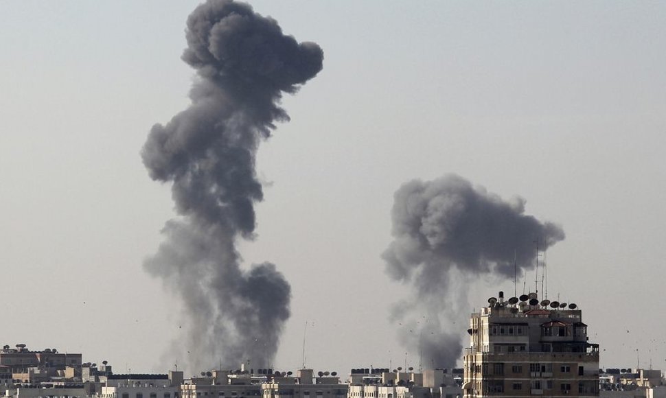 Po raketų sprogimų kyla dūmai virš Gazos miesto