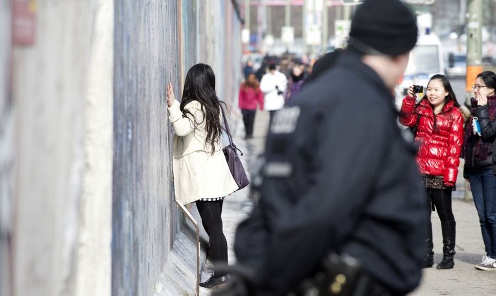 Merginos fotografuojasi šalia Berlyno sienos