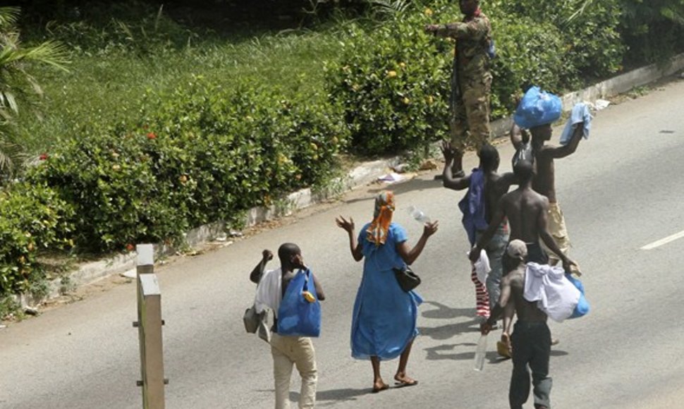 Vietos gyventojai iškėlę rankas eina pro Laurento Gbagbo kareivius