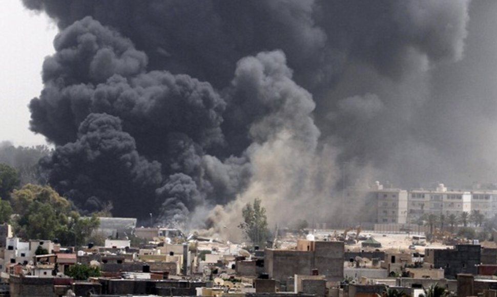 Po NATO oro atakų Tripolyje kyla juodi dūmai.