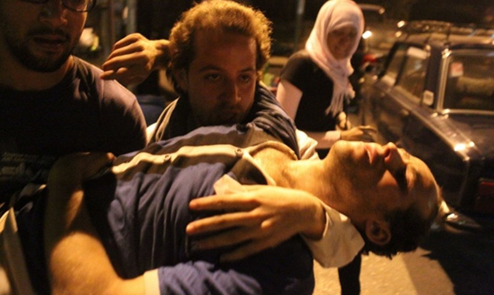 Vyrai neša sužeistą protestuotoją.