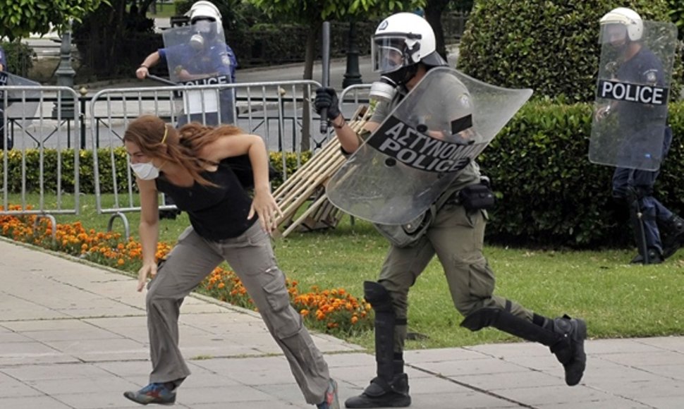 Protestuotoja bėga nuo policininko.