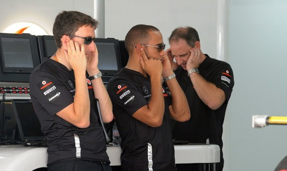 Lewis Hamiltonas (centre) užsikimešęs ausis kol bandomas „Formulės-1“ variklis