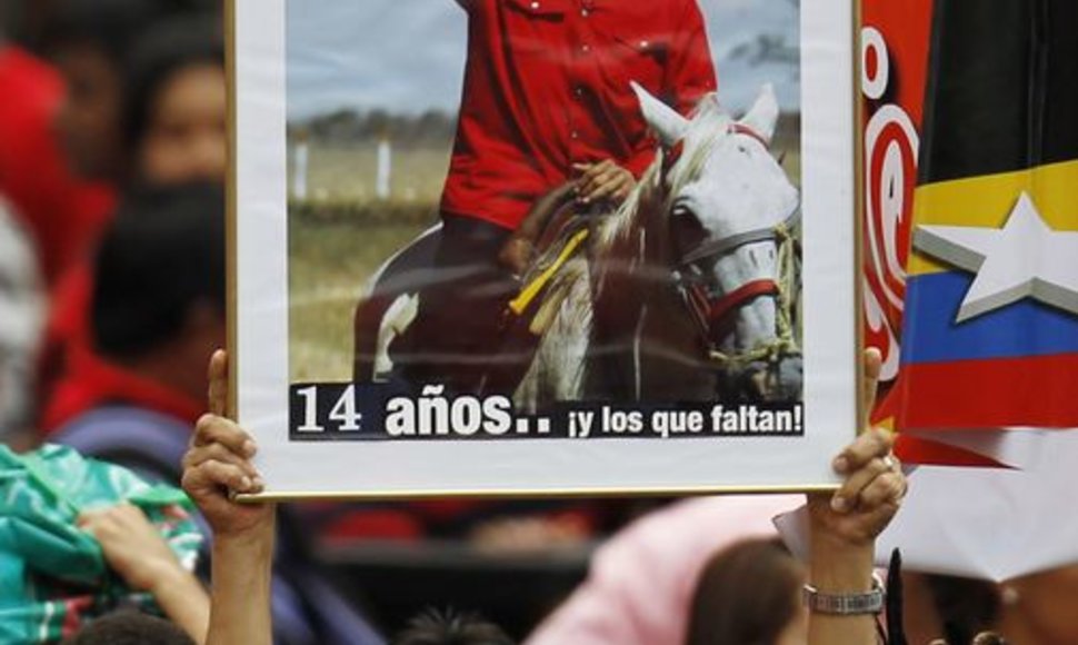 Žmogus, laikantis plakatą, vaizduojantį Venesuelos prezidentą Hugo Chavezą