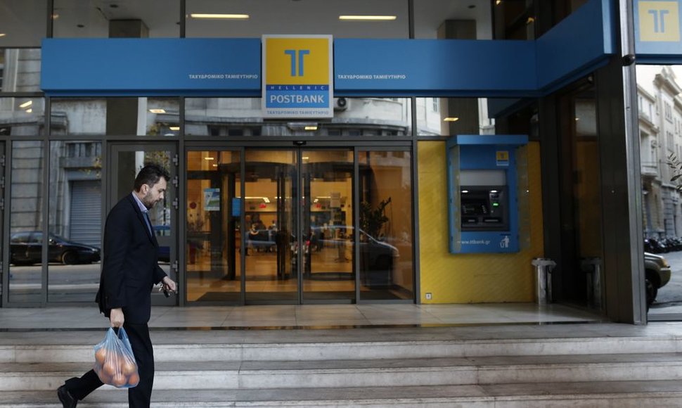 Žmogus eina pro „Hellenic Postbank“ banką Atėnuose