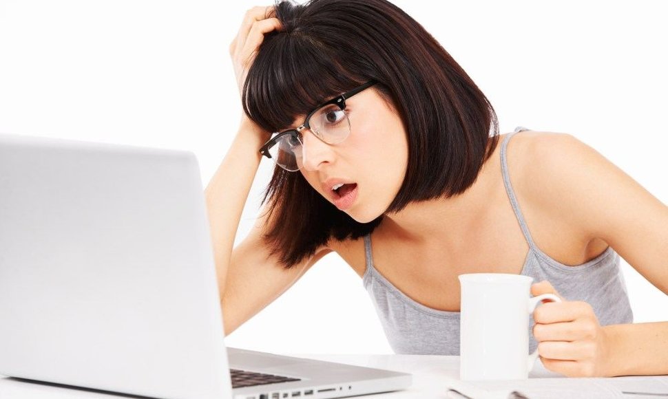 Mergina sėdinti prie kompiuterio ir gerianti kavą