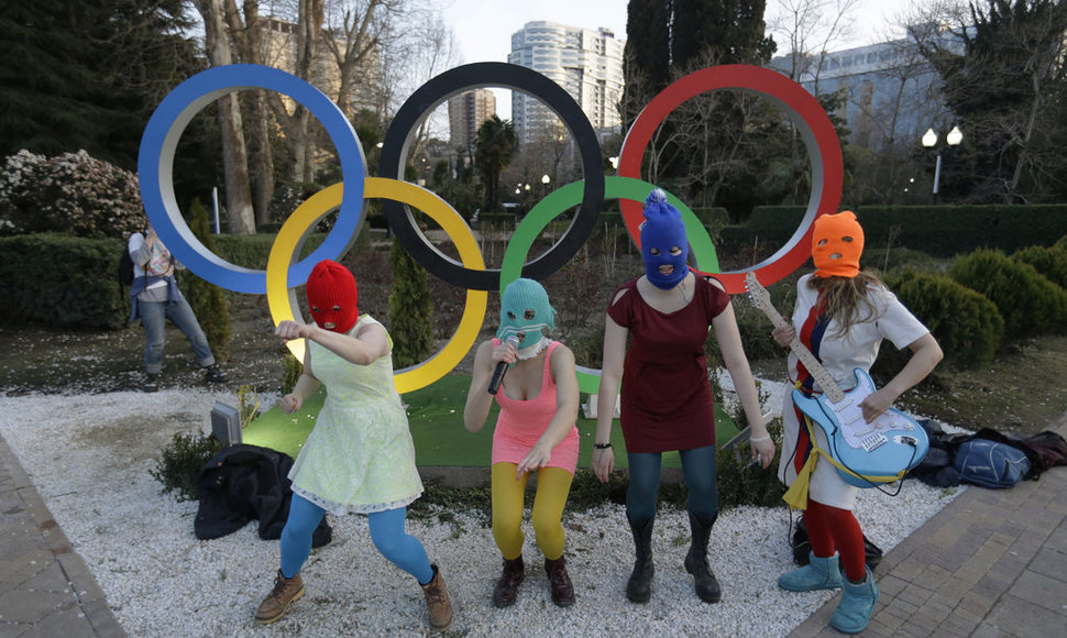 Members of the punk group Pussy Riot, including Nadezhda Tolokonnikova in the aqua balaclava, center, and Maria Alekhina in the red balaclava, left, perform next to the Olympic rings in Sochi, Russia, on Wednesday, Feb. 19, 2014. Cossack militia attacked the punk group with horsewhips earlier in the