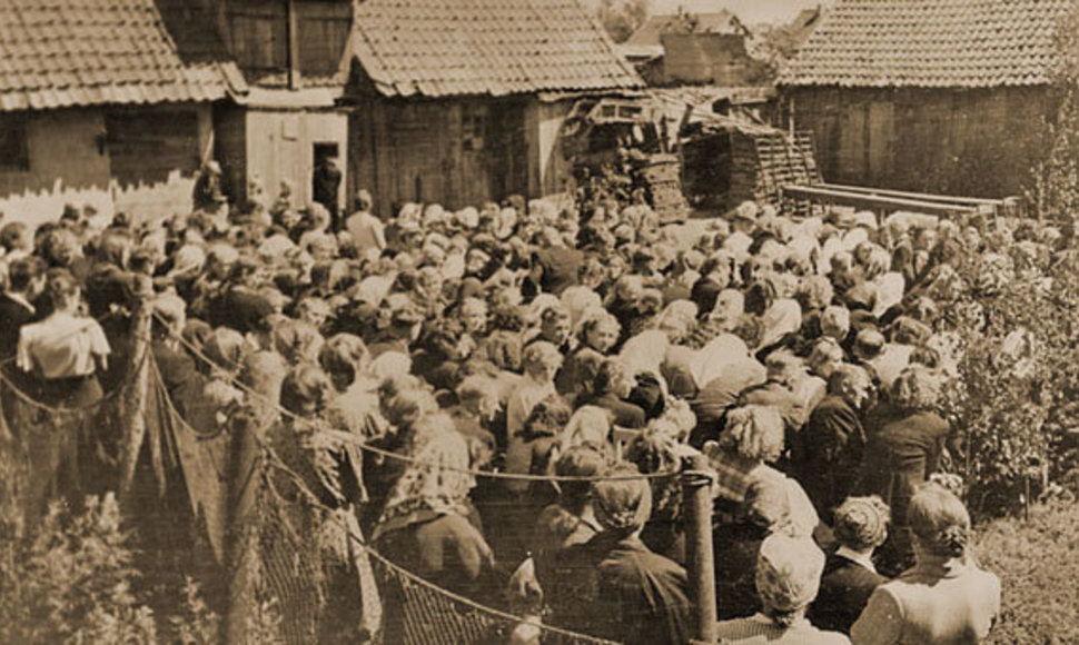 Apie 1954 m. pamaldos žvejo Kaitinio namų kieme Minijos g., kai liuteronai dar neturėjo savo maldos namų. Galbūt, tai Misijų sekmadienio pamaldos. R.Moras mano, kad tai Albino Stubros nuotrauka. 