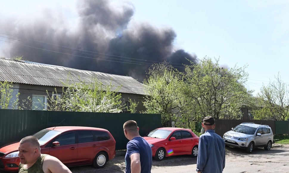 Gyventojai stebi dūmus kilstant iš gaisro po šaudymo.