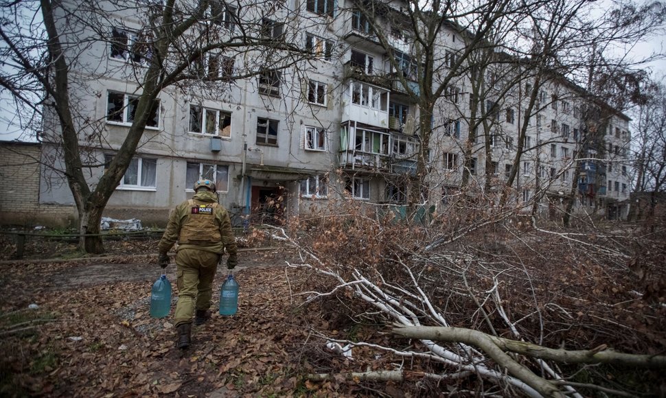 Policininkas Krasnohorivkoje neša vandenį vietos gyventojams. / Anna Kudriavtseva / REUTERS