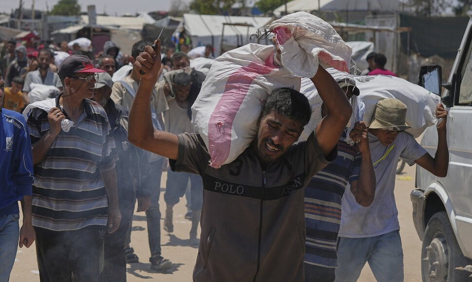 Palestiniečiai ne&scaron;asi maisto produktų mai&scaron;us i&scaron; pagalbos skirstymo centro / Abdel Kareem Hana / AP