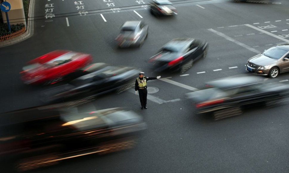 Policininkas reguliuoja eismą intensyvaus eismo gatvėje Šanchajuje 