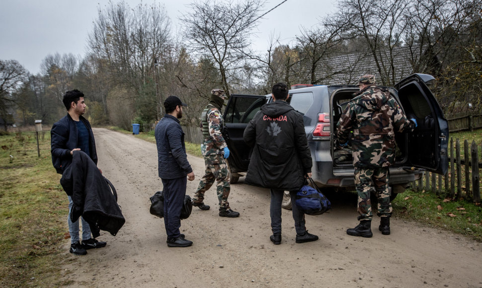 Pasieniečiai Musteikos kaime (Varėnos r.) veda sulaikytus migrantus į tarnybinį automobilį