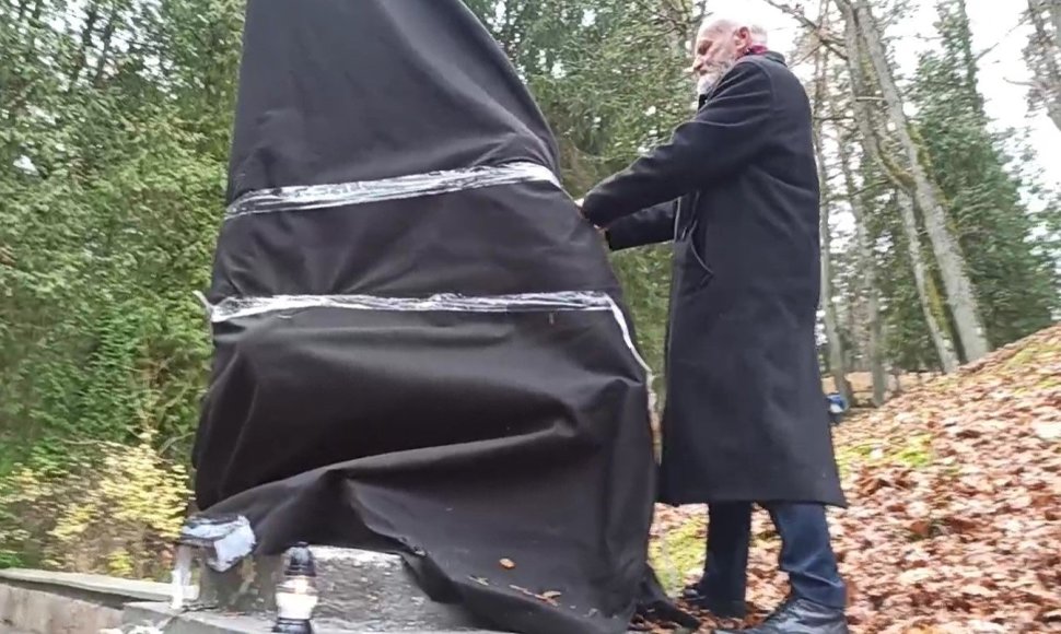 Kazimieras Juraitis plėšia juodą audeklą nuo sovietinės skulptūros Antakalnio kapinėse