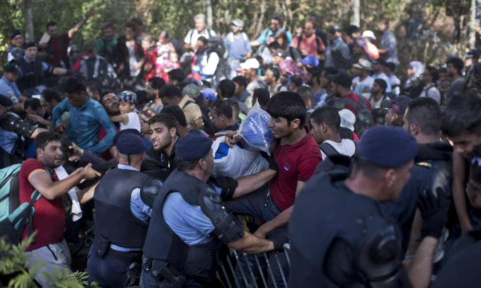 Migrantai Tovarnike braunasi pro pareigūnų užtvarą.