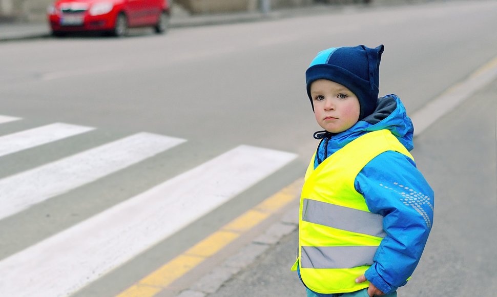 Vaikas vilki liemene su šviesą atspindinčiomis juostomis