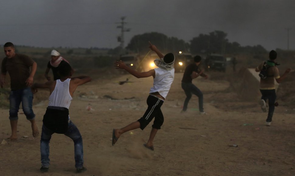 Palestiniečiai mėto akmenis į Izraelio pareigūnus.