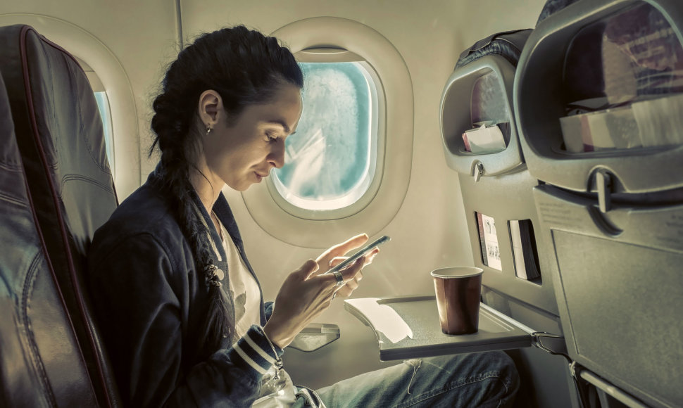 Mergina, kuri lėktuve naudojasi telefonu