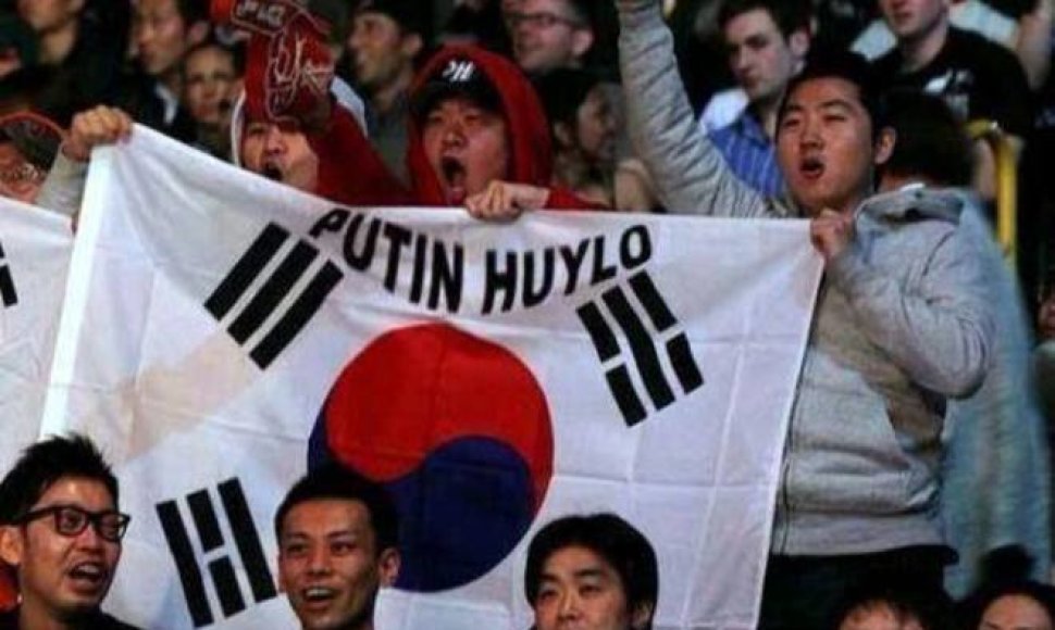 Pietų Korėjos sirgaliai su vėliavą, ant kurios yra užrašas „Putin Huylo“