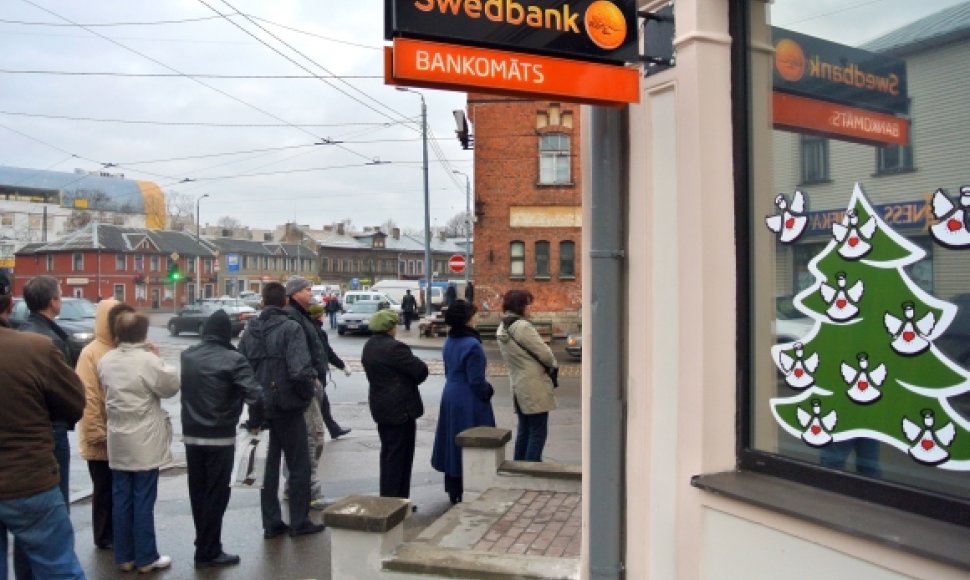 Žmonės stoja į ilgą eilę Rygoje, kad atsiimtų savo pinigus iš „Swedbank“ bankomato.