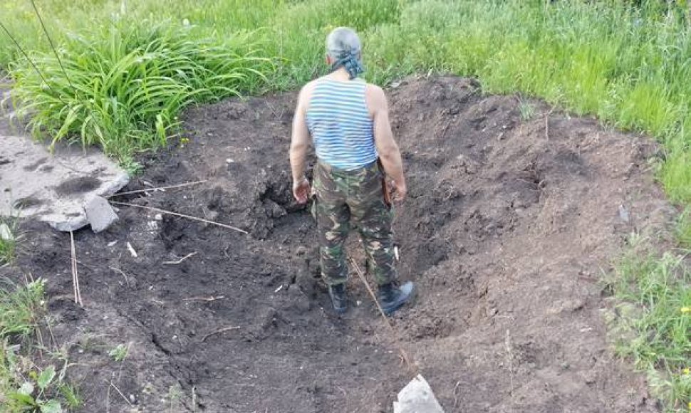 Ukrainos karys stovi haubicos smūgio paliktame krateryje.