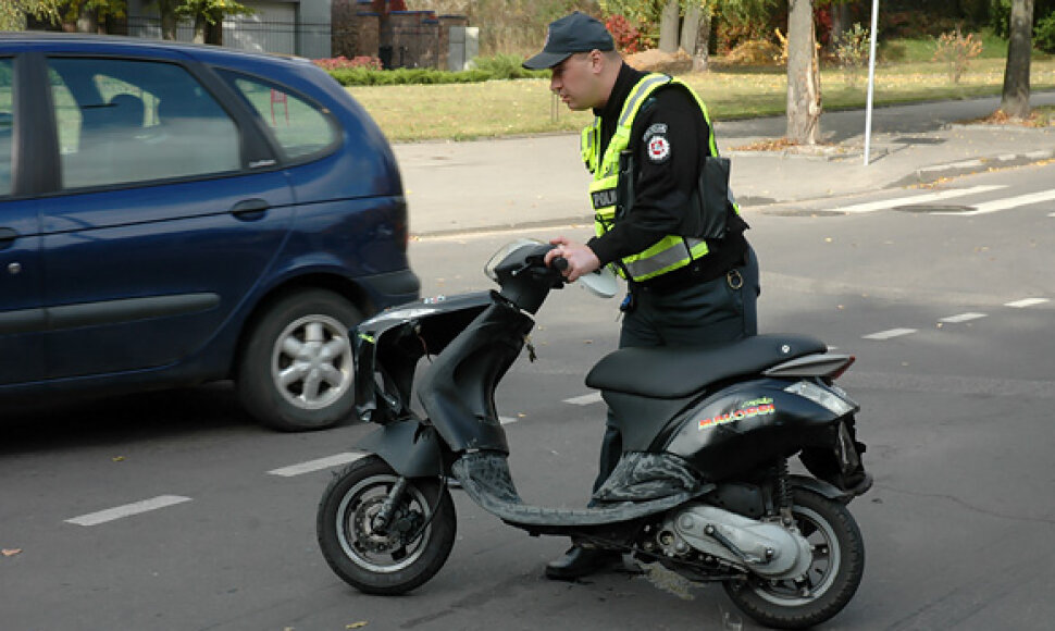 Policininkas apžiūri sudaužytą mopedą