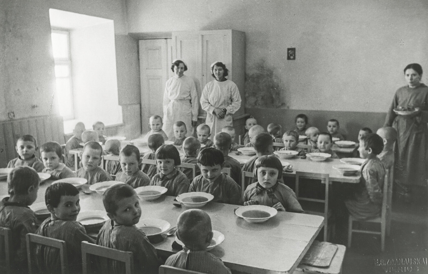 Prie&scaron;mokyklinio amžiaus karo atbėgėlių vaikučiai prie stalo pietų metu. Įdomu, kas tose mažose jų galvutėse, tur būti dar prisimenančiose, kad vos prie&scaron; keletą mėnesių jie pietaudavo savo tėvų namuose, o dabar tenka nuo &scaron;eimų atskirtiems, dažnai ir tėvę netekus, glaustis ir misti tarp nepažįstamų žm