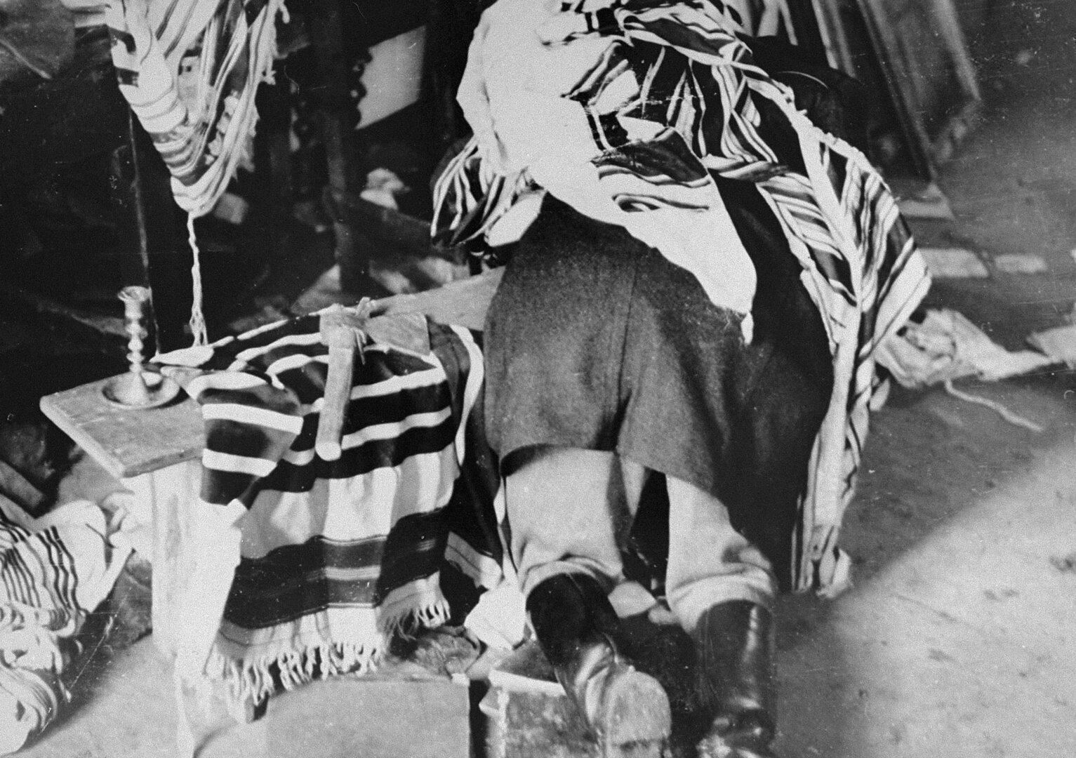 1941 m. birželio mėn. per pogromą Kaune lietuviai nusiaubė sinagogą. Pridengtas maldos &scaron;aliku vyro kūnas guli ant suolo sinagogoje, &scaron;alia jo guli kirvis