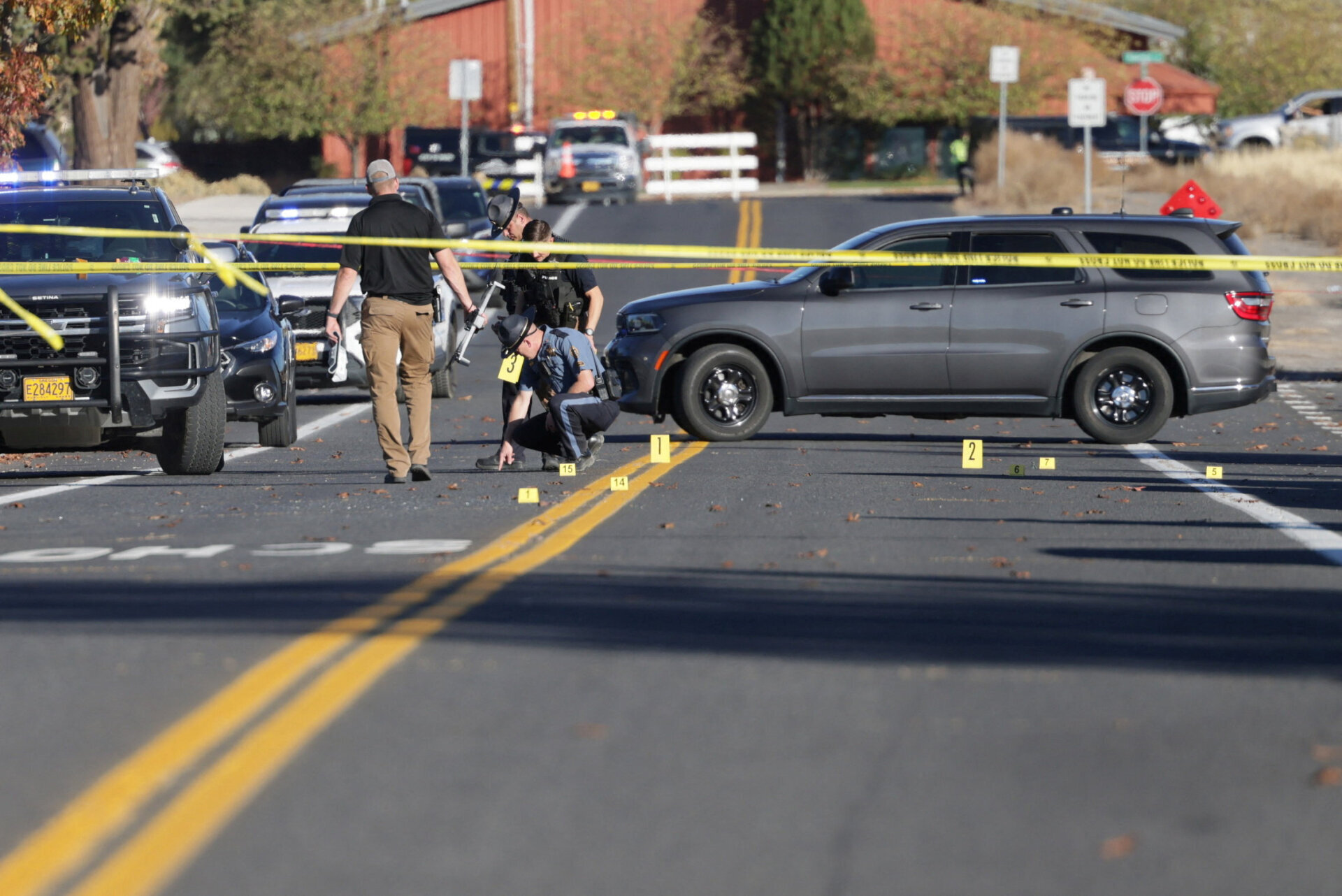 Police officers investigating a shooting scene on a closed street